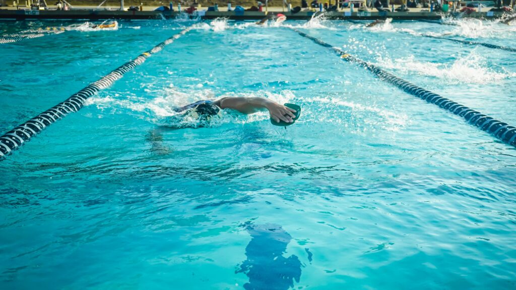 An adult swimmer practicing freestyle in an outdoor Olympic-size pool.
